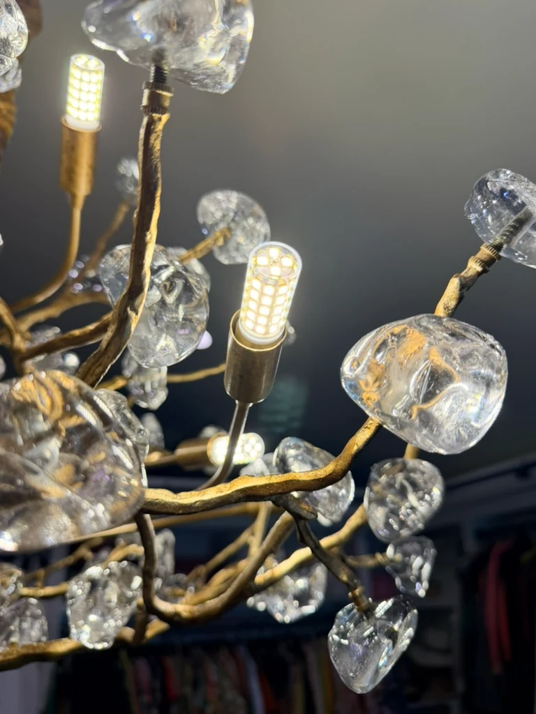Detail of illuminated lamps, gold branches and clear decorative pieces on the chandelier