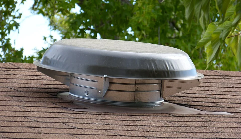 Metal weatherproof cap over a roof-mounted attic ventilator.