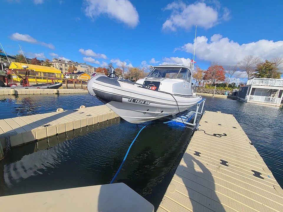 A boat supported by an Aegis lift beside a floating dock. Equipment example; not a Guardian installation.