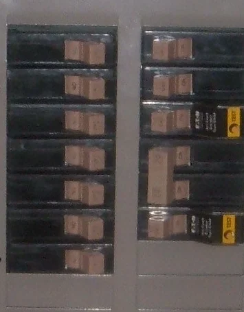 Detail photograph of residential branch-circuit breaker handles behind the protective panel front