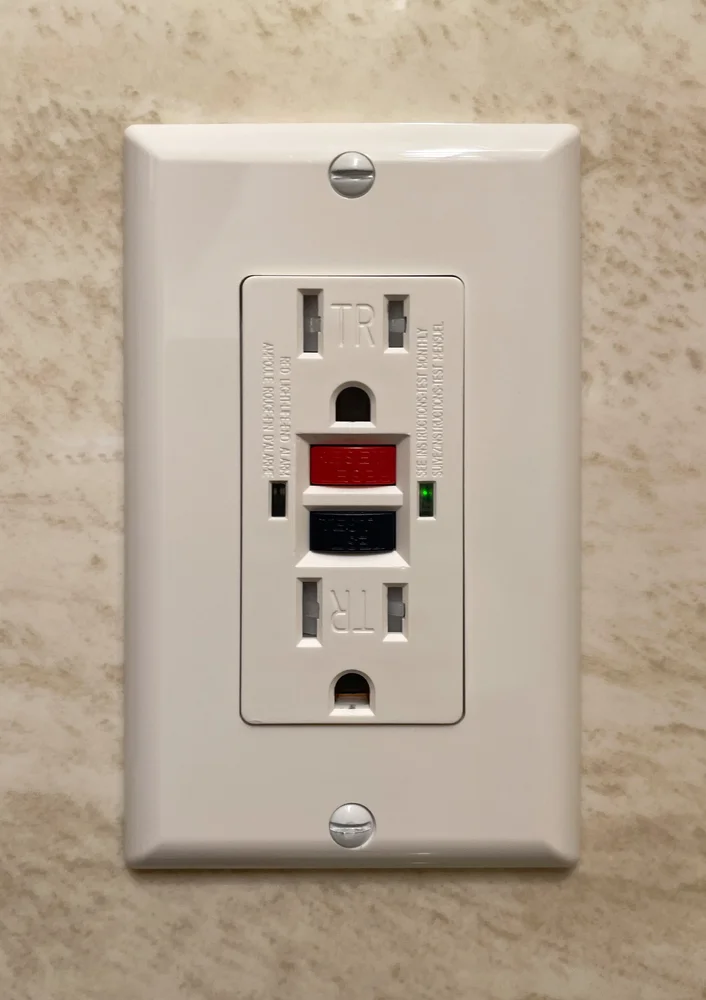 Photograph of a GFCI receptacle with red RESET and black TEST buttons
