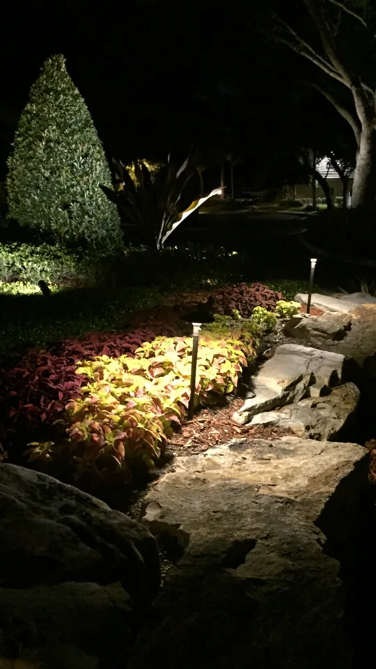 Illuminated path light beside a stone garden walkway at night.