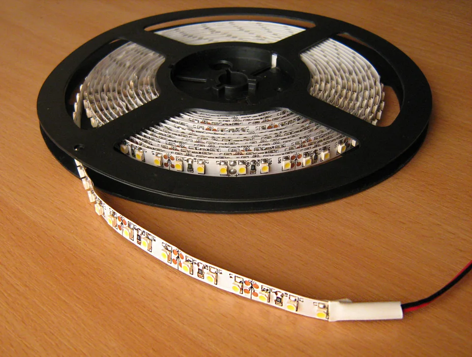 Flexible LED strip partly unrolled from a black reel.