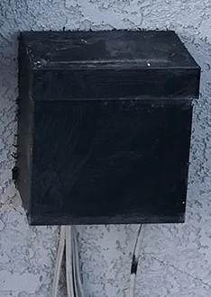 Black outdoor low-voltage landscape-lighting transformer enclosure mounted on stucco.