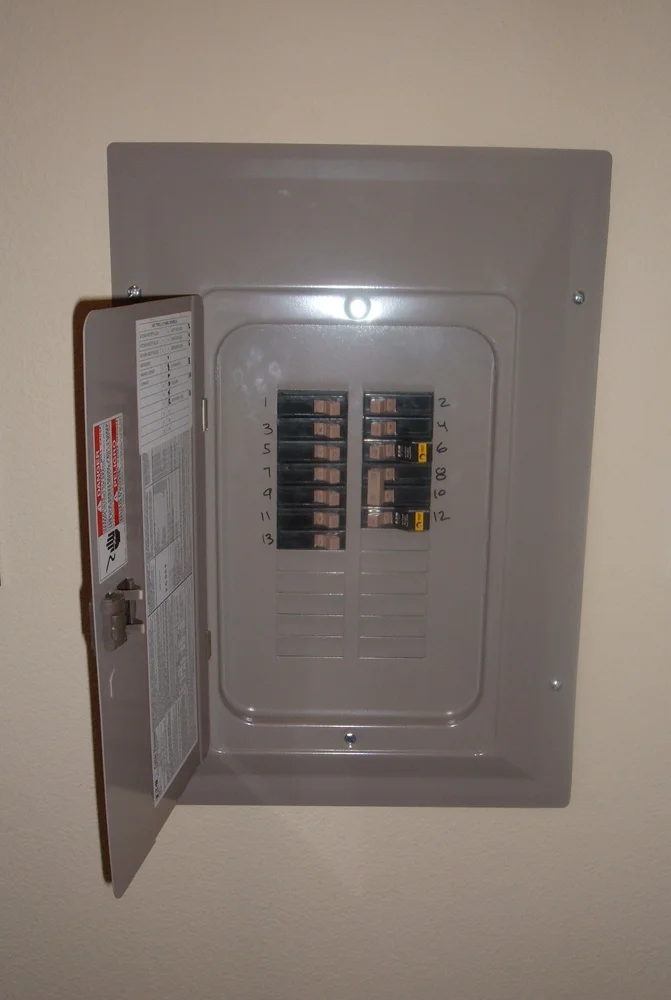 Photograph of a residential breaker panel with its outer door open and protective front in place