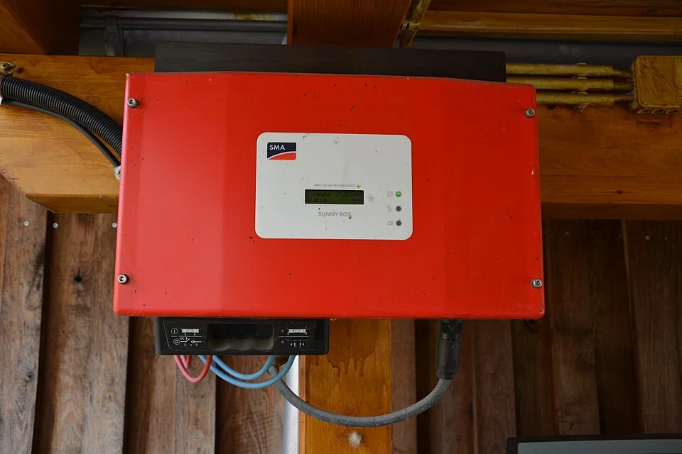 Red SMA Sunny Boy solar inverter mounted on a wooden wall.