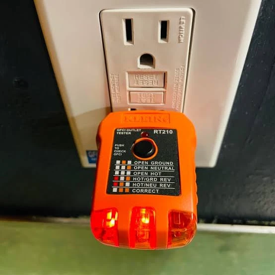 GFCI receptacle with a plug-in electrical tester. A tester photograph does not establish the condition of another outlet.