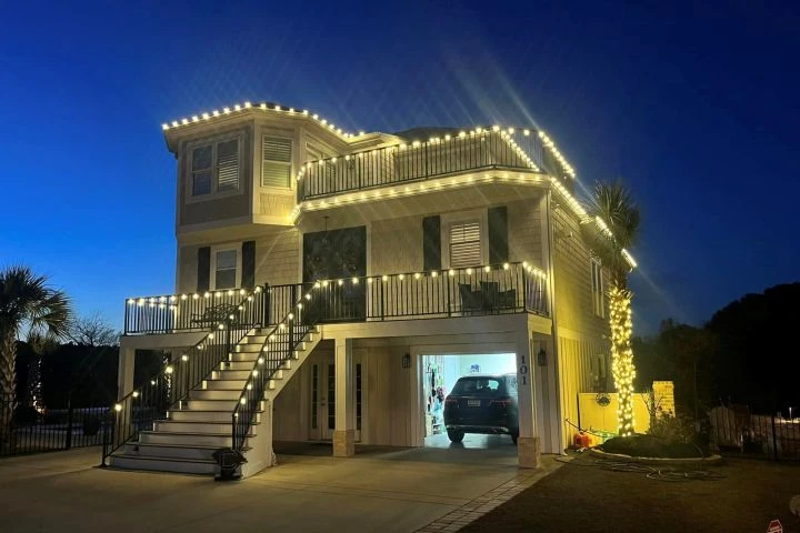 House with decorative lighting along the roof, stairs and columns. Outdoor-lighting example; product type and permanent rating are not established by the photograph.