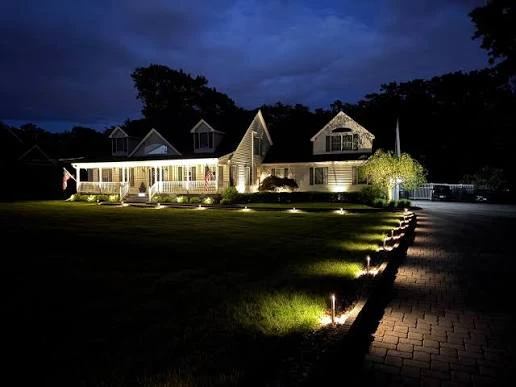Landscape lights illuminating a walkway and the front of a home at night.