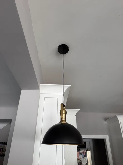 The finishing touch. Close detail of a black pendant shade and brass fitting.