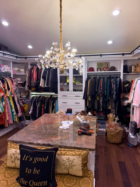 A room with a centerpiece. The installed decorative chandelier above a dressing-room island.