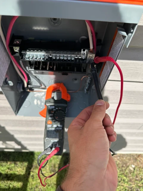 Measurements on site. A clamp meter used at an open electrical disconnect during testing.