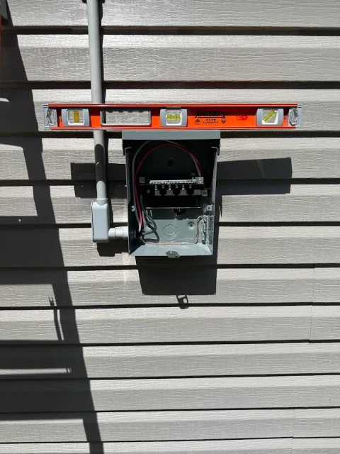 Exterior disconnect installation. An open exterior electrical disconnect mounted on horizontal siding during installation.