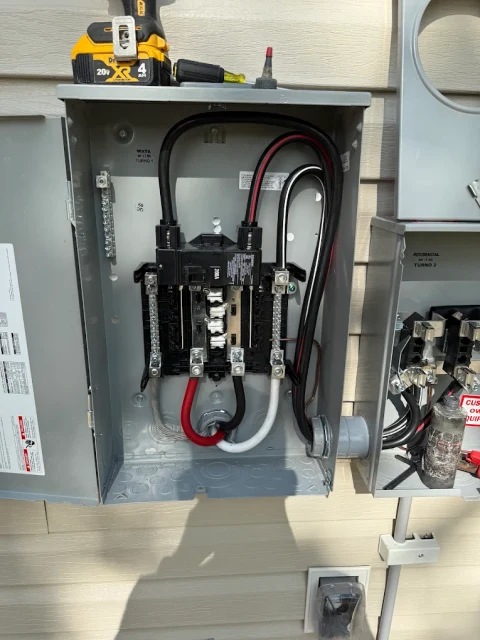 Service equipment up close. An open electrical service enclosure with conductors, breakers and conduit visible during work.